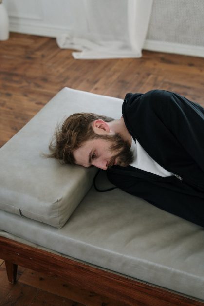 man in black long sleeve shirt lying on gray couch